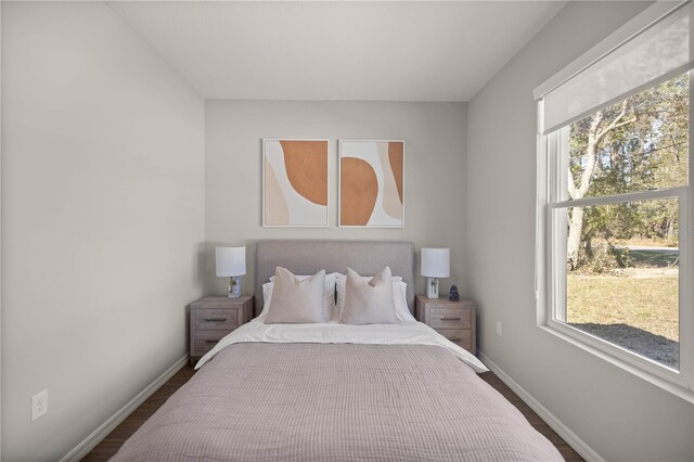 bedroom with dark hardwood / wood-style flooring and multiple windows