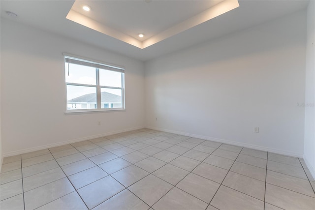 tiled empty room featuring a tray ceiling