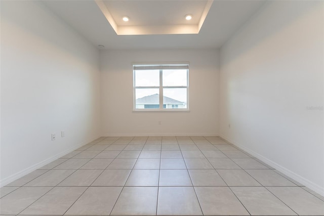 tiled spare room featuring a tray ceiling