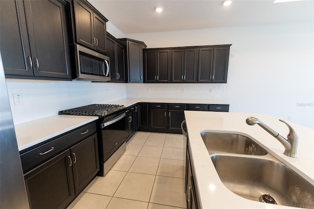 kitchen featuring appliances with stainless steel finishes, light tile patterned flooring, sink, and backsplash