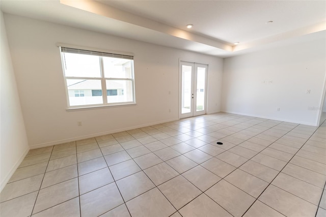 unfurnished room with a tray ceiling and light tile patterned flooring