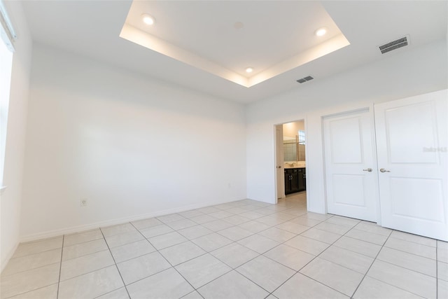 tiled empty room with a raised ceiling