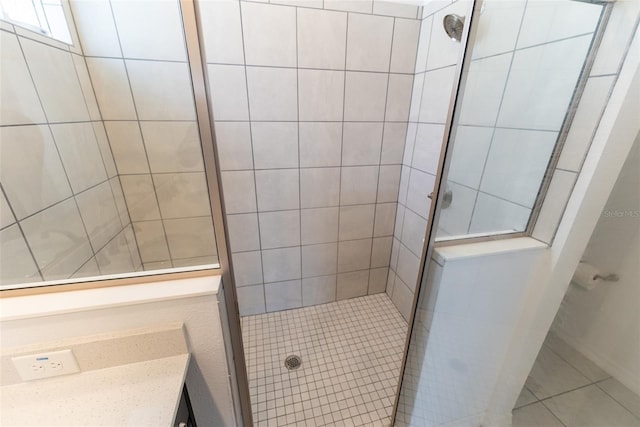 bathroom with a tile shower and vanity