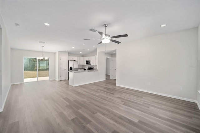 unfurnished living room featuring light wood-type flooring, ceiling fan with notable chandelier, and sink