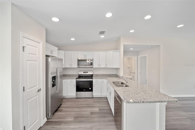 kitchen featuring appliances with stainless steel finishes, white cabinetry, light stone counters, and sink