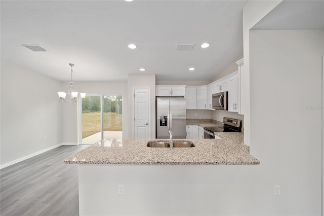 kitchen with kitchen peninsula, appliances with stainless steel finishes, white cabinetry, and sink