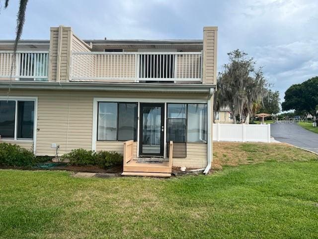 back of property with a yard and a balcony