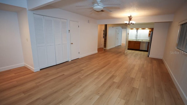 interior space with light hardwood / wood-style flooring, ceiling fan with notable chandelier, and a textured ceiling