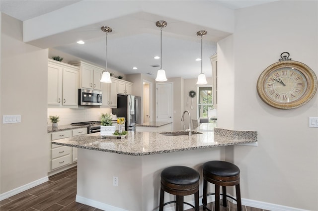 kitchen with kitchen peninsula, appliances with stainless steel finishes, sink, pendant lighting, and dark hardwood / wood-style floors