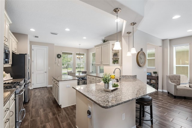 kitchen featuring kitchen peninsula, hanging light fixtures, dark hardwood / wood-style floors, and appliances with stainless steel finishes