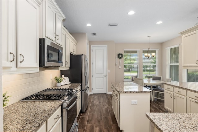 kitchen featuring light stone countertops, stainless steel appliances, dark hardwood / wood-style floors, decorative light fixtures, and a kitchen island