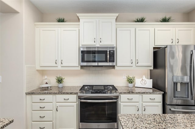 kitchen with backsplash, light stone counters, white cabinetry, and stainless steel appliances