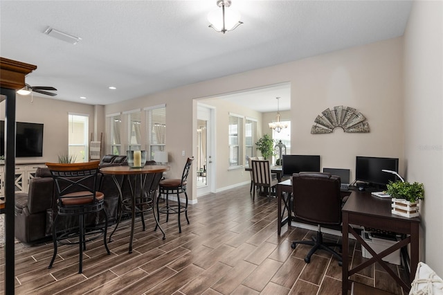 home office with ceiling fan with notable chandelier and dark hardwood / wood-style flooring