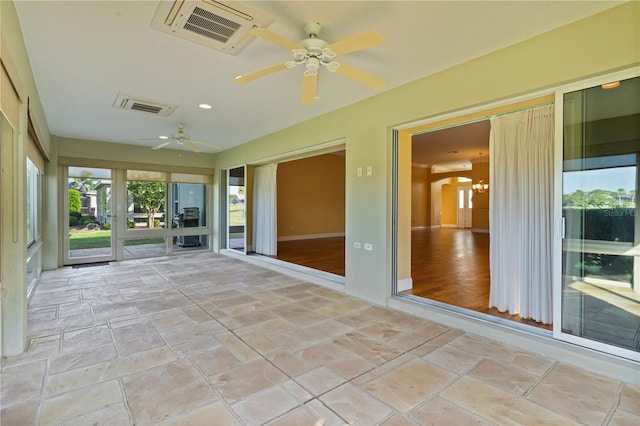 unfurnished sunroom with ceiling fan with notable chandelier