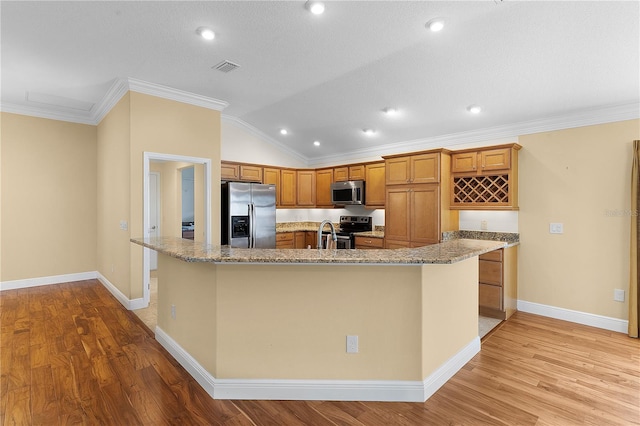 kitchen with lofted ceiling, a spacious island, ornamental molding, and appliances with stainless steel finishes