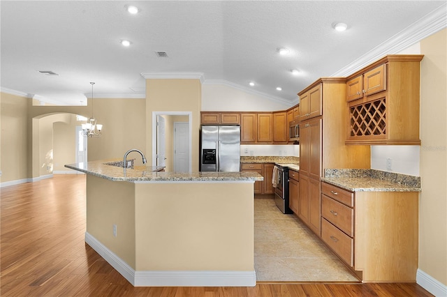 kitchen with ornamental molding, stainless steel appliances, vaulted ceiling, hanging light fixtures, and an island with sink