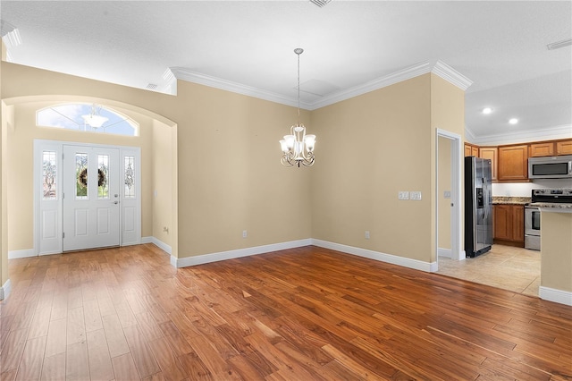 entryway with light hardwood / wood-style flooring, crown molding, and a chandelier