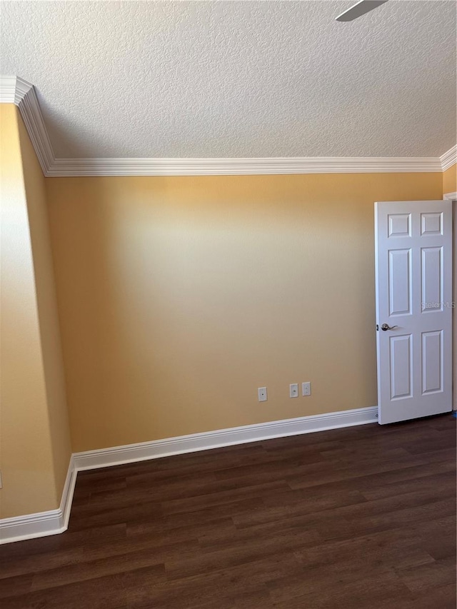 empty room featuring a textured ceiling, dark hardwood / wood-style floors, and ornamental molding