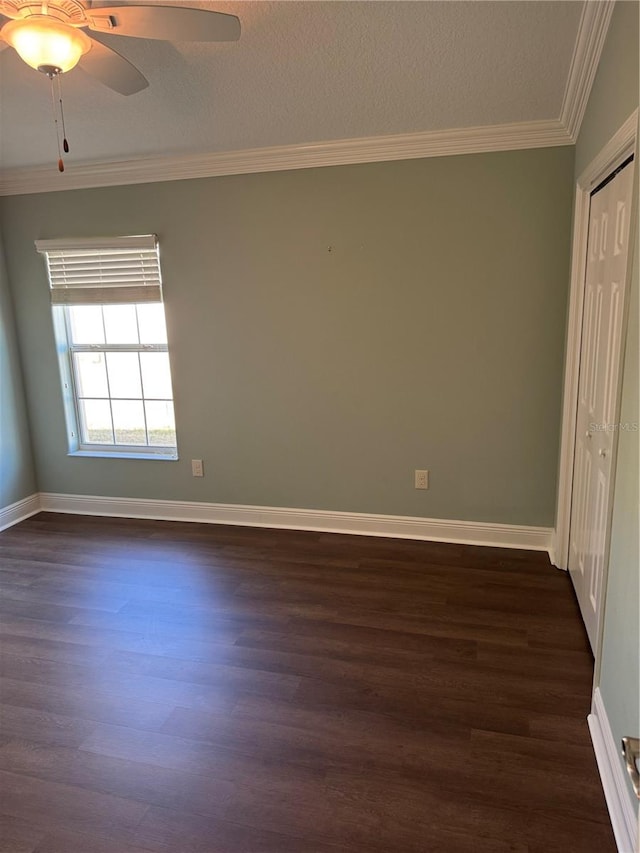 empty room with dark hardwood / wood-style floors, ceiling fan, and crown molding