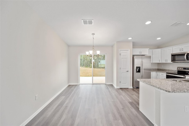 kitchen with appliances with stainless steel finishes, decorative light fixtures, light hardwood / wood-style flooring, white cabinets, and a chandelier