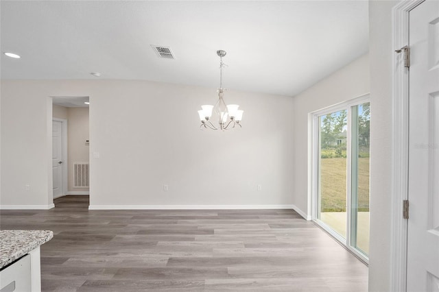 unfurnished dining area with a chandelier and wood-type flooring