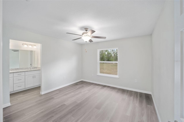 unfurnished bedroom featuring connected bathroom, ceiling fan, and light wood-type flooring