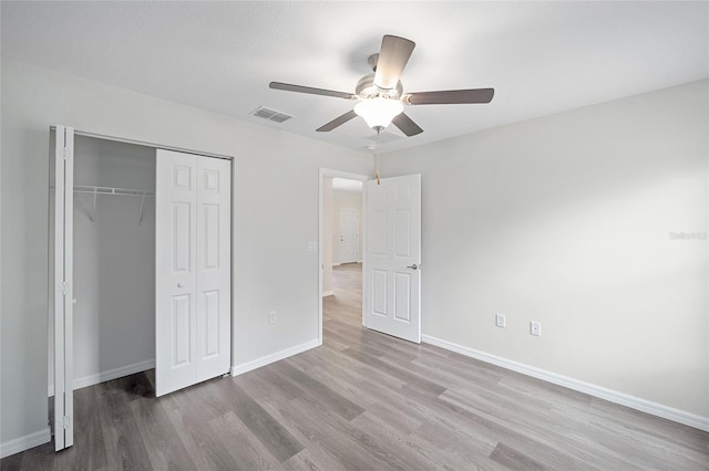 unfurnished bedroom with ceiling fan, light hardwood / wood-style flooring, and a closet