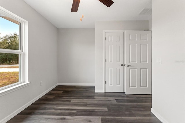 empty room with dark hardwood / wood-style floors, plenty of natural light, and ceiling fan