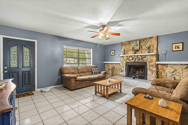 tiled living room with a stone fireplace, a textured ceiling, and ceiling fan