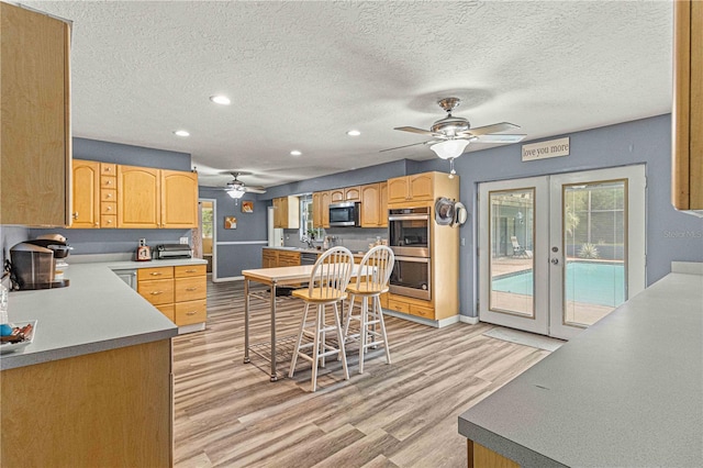 kitchen with ceiling fan, appliances with stainless steel finishes, light hardwood / wood-style floors, a textured ceiling, and french doors