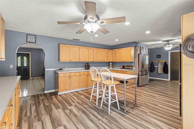 kitchen featuring light brown cabinets, stainless steel fridge with ice dispenser, hardwood / wood-style floors, and a textured ceiling