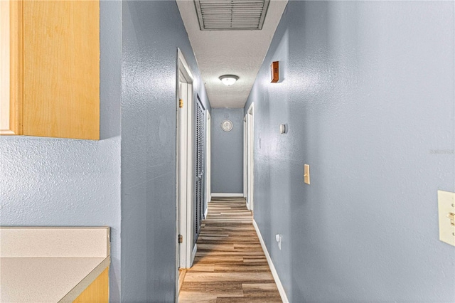 hallway featuring hardwood / wood-style flooring and a textured ceiling