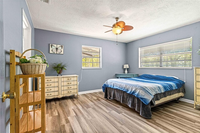 bedroom with ceiling fan, a textured ceiling, and light hardwood / wood-style flooring