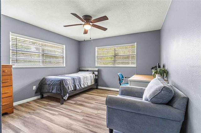 bedroom with ceiling fan, light hardwood / wood-style floors, and a textured ceiling