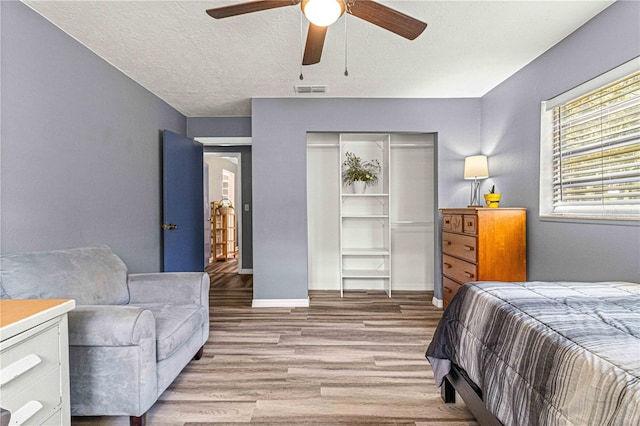 bedroom with ceiling fan, light hardwood / wood-style floors, a closet, and a textured ceiling