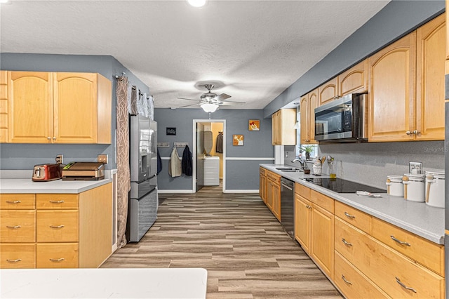 kitchen featuring sink, stainless steel appliances, light hardwood / wood-style floors, a textured ceiling, and light brown cabinets