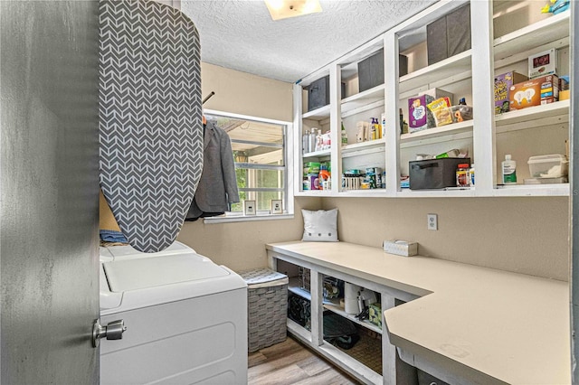 washroom featuring washer and dryer, light hardwood / wood-style floors, and a textured ceiling