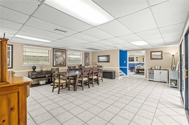 dining room with a drop ceiling and light tile patterned flooring