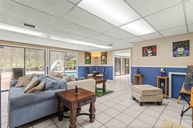 living room featuring a paneled ceiling and tile patterned floors