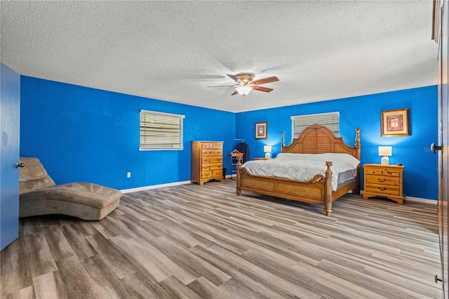 bedroom with a textured ceiling, light hardwood / wood-style flooring, and ceiling fan