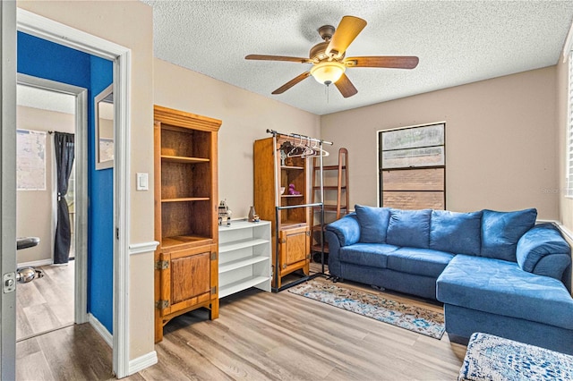 living room featuring hardwood / wood-style flooring, ceiling fan, and a textured ceiling