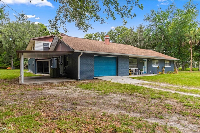 ranch-style house with a carport, a garage, a front lawn, and central air condition unit