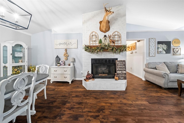 living room with a brick fireplace, dark hardwood / wood-style flooring, and vaulted ceiling