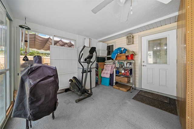 workout room with ceiling fan and wood walls