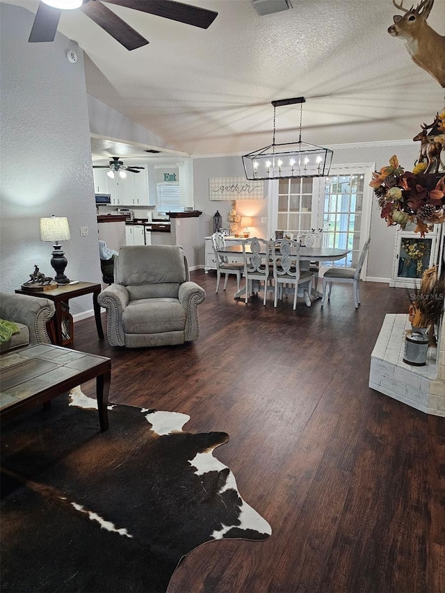 living room featuring vaulted ceiling, ceiling fan, a textured ceiling, and dark hardwood / wood-style floors