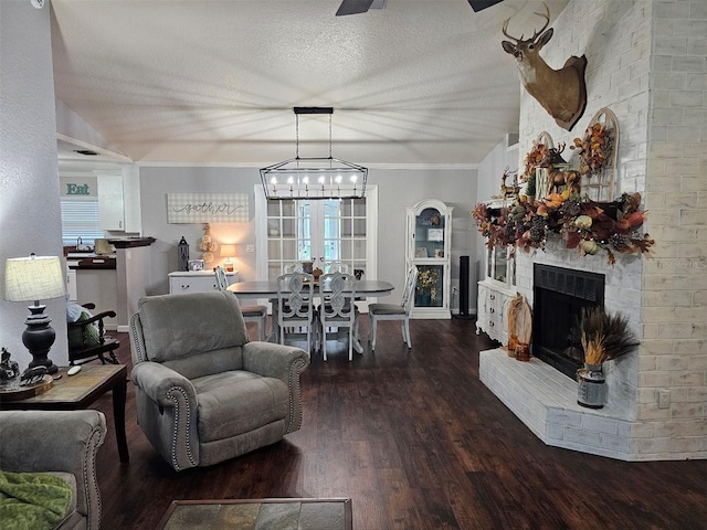 living room featuring lofted ceiling, crown molding, hardwood / wood-style flooring, a fireplace, and a textured ceiling