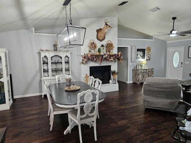 dining area featuring a fireplace, vaulted ceiling, and dark wood-type flooring