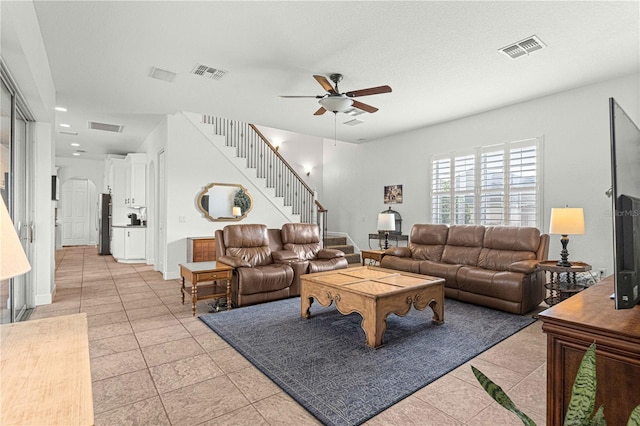 living room featuring ceiling fan, a textured ceiling, and light tile patterned floors