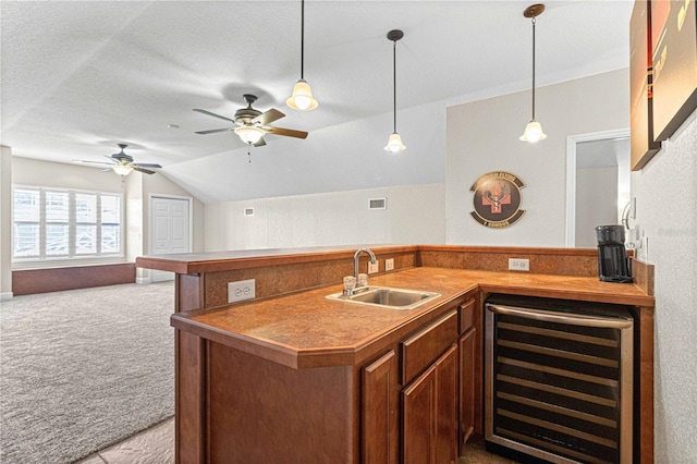 kitchen featuring carpet, beverage cooler, open floor plan, lofted ceiling, and a sink