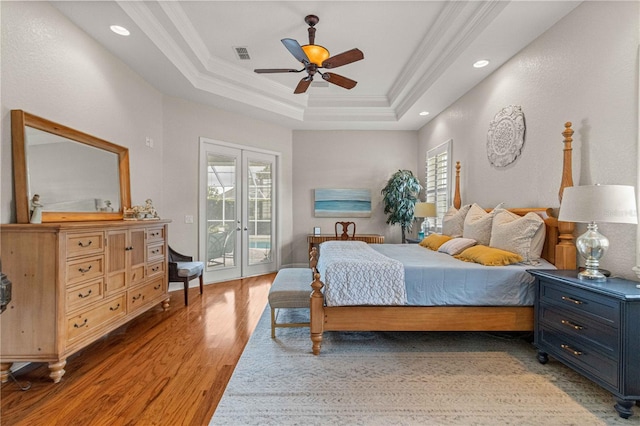 bedroom with a raised ceiling, access to outside, ceiling fan, and multiple windows